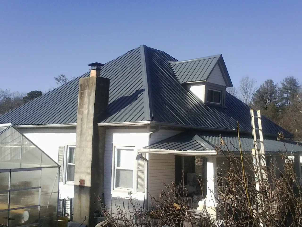 Dark blue standing seam metal roof on a white farmhouse with dormer — Slate & Tile Roof Repair by Roofing Brothers in Haverhill
