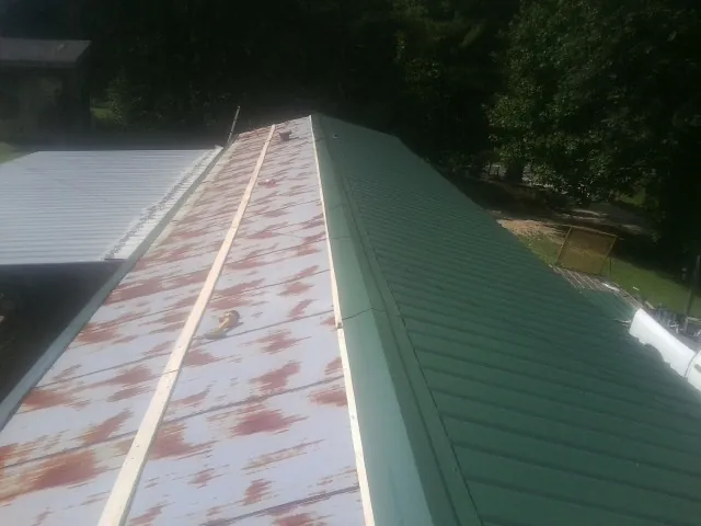 Old rusted panels beside newly installed green metal roofing — Wind Damage Roof Repair by Roofing Brothers in Haverhill